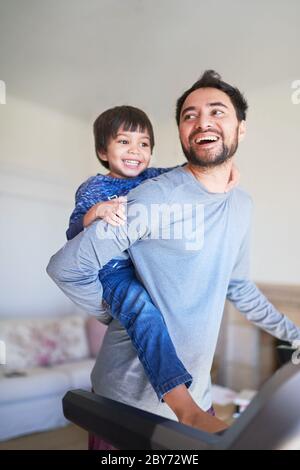 Felice padre piggybacking figlio sulla pedana mobile Foto Stock