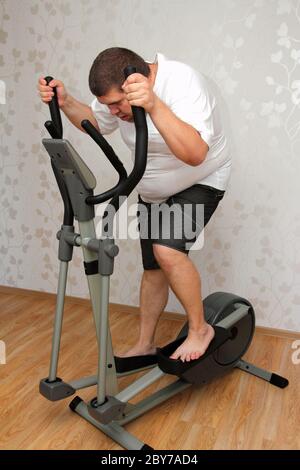 uomo in sovrappeso che si esercita sull'istruttore Foto Stock