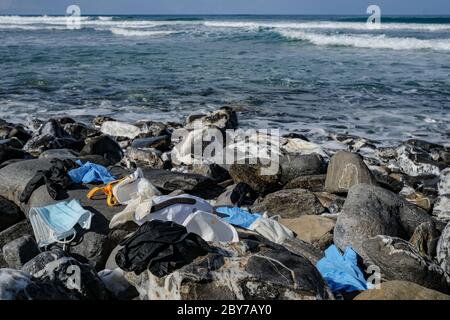 Rifiuti medici, maschere usate sporche e guanti di plastica rifiuti gettati sulla costa rocciosa del mare, coronavirus covid19 inquinamento Foto Stock