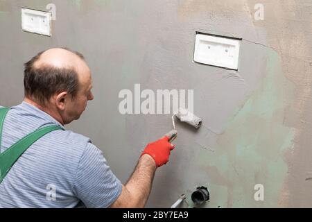 Ristrutturazione del bagno. Lavoratore di costruzione. Isolamento di umidità minerale. Durante il lavoro. Foto Stock