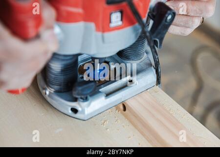 Le mani del falegname tengono una pialla elettrica Woodwork vicino vista Foto Stock