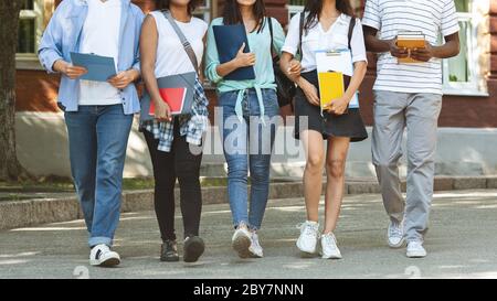 Immagine ritagliata degli studenti universitari che camminano all'aperto vicino al campus dopo le lezioni Foto Stock