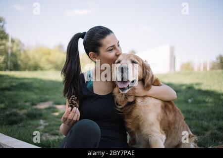 Bella donna coccolarsi e baciare cane all'aperto Foto Stock