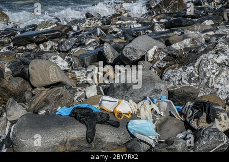 Rifiuti medici, maschera virus e guanti di plastica spazzatura scartata sulla costa rocciosa del mare, coronavirus covid19 inquinamento Foto Stock