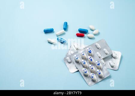 Informazioni di base sulla medicina farmaceutica. Blister di pillole divertenti con sorrisi volti su blu. Assistenza sanitaria, pillole giornaliere, antidepressivi, medicina, trattamento c Foto Stock