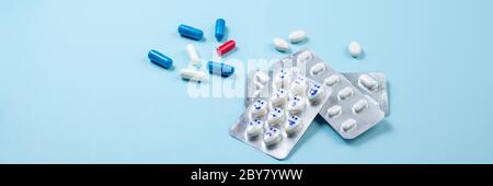 Blister di pillole divertenti con sorrisi volti su sfondo blu. Assistenza sanitaria, pillole giornaliere, antidepressivi, medicina, concetto di trattamento. Spazio per la copia, lungo Foto Stock