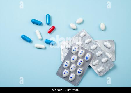 Informazioni di base sulla medicina farmaceutica. Blister di pillole divertenti con sorrisi volti su blu. Assistenza sanitaria, pillole giornaliere, antidepressivi, medicina, trattamento c Foto Stock