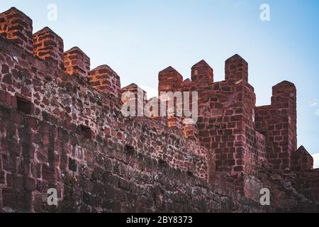Facciata interna e torre di un castello medievale, fatto di massi rossi rodeno Foto Stock