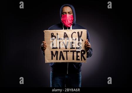Foto di un ragazzo americano afro frustrato tenere banner di cartone chiedere inizio supporto valore diritti umani indossare rosso maschera bendanna ponticello isolato su nero Foto Stock