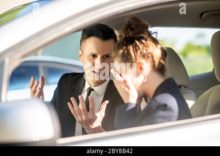 Uomo d'affari serio e donna piangente in un'automobile Foto Stock