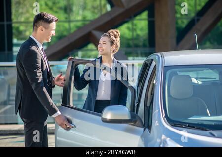 Uomo che apre una porta di automobile per una donna. Foto Stock