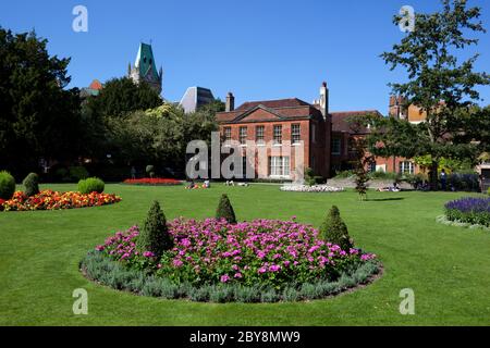 I giardini dell'abbazia con la Casa dell'abbazia e la torre dell'orologio della Guildhall, Winchester, Hampshire, Inghilterra, Regno Unito Foto Stock