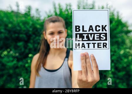 Donna che mostra carta contro il razzismo Foto Stock