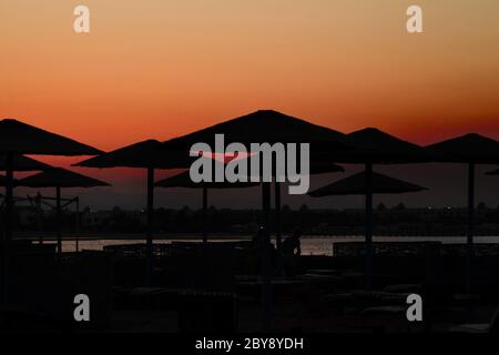 Sunrise egiziano sotto ombrelloni sulla spiaggia Foto Stock