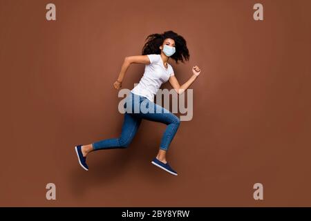 Vista a lunghezza intera delle dimensioni del corpo di lei attraente motivata sana energica ragazza con capelli ondulati indossare garza maschera di sicurezza salto corsa stop pandemia Foto Stock