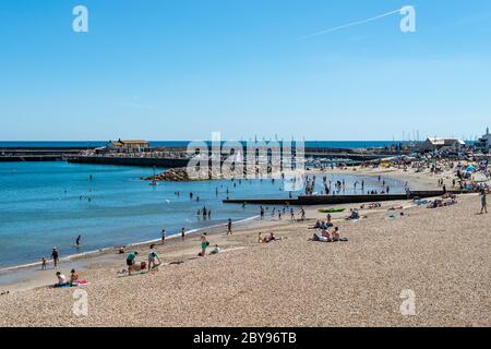 Lyme Regis, Dorset, Regno Unito. Persone in spiaggia e durante una giornata estiva soleggiata. Foto Stock