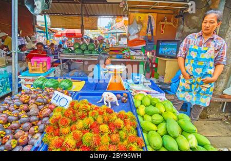 MAEKLONG, THAILANDIA - 13 MAGGIO 2019: Il piccolo gattino gioca sul vassoio con i rambutan e i mangostani di una bancarella di frutta nel mercato ferroviario di Maeklong, su M. Foto Stock