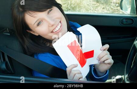 Allegro giovane driver femmina sistemando il suo segno L Foto Stock