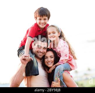I genitori dare ai bambini piggyback rides Foto Stock