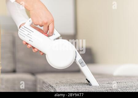 Donna che aspira mobili in una casa con un aspirapolvere portatile  portatile portatile Foto stock - Alamy