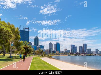 Runner sul lungofiume e pista ciclabile che guarda verso lo skyline del centro, Riverside Drive, David Carr Memorial Park, Perth, Australia Foto Stock