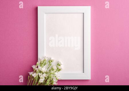 Bianco mockup cornice foto vuota con mouse-orecchio fiori di ceci su sfondo rosa viola, vista dall'alto spazio copia Foto Stock
