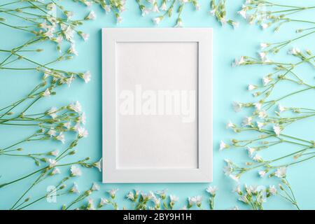 Bianco mockup cornice foto vuota con mouse-orecchio fiori di ceci su sfondo blu, vista dall'alto spazio copia Foto Stock