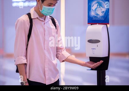 Primo piano delle mani con il dispenser automatico per gel di alcol a mani lavate per disinfettare e disinfettare i patogeni del Coronavirus (COVID-19). Foto Stock