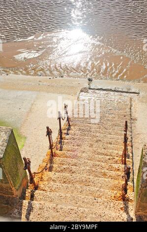 Scalini di pietra e catena arrugginita che collegano la barriera in un muro di mare che conduce al mare e alla spiaggia di Blackpool Foto Stock