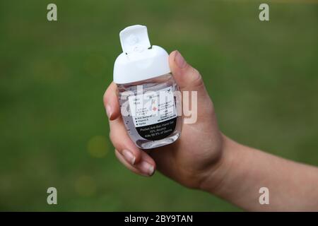 Mani che tengono 70% alcool disinfettante mani durante la pandemia di Covid 19, giugno 2020 Foto Stock