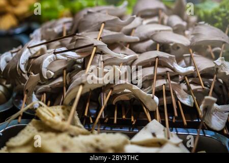 Funghi appena tagliati su bastoncini di legno, pronti per essere grigliati per strada nel quartiere musulmano, città di Xian, Cina Foto Stock