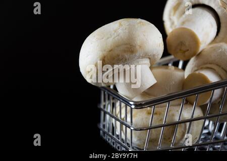funghi champignon in un carrello su sfondo nero 2 Foto Stock