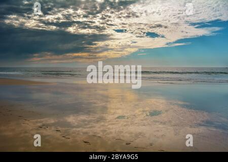 Riflesso delle nuvole sull'oceano, camminando da soli sulla spiaggia Foto Stock