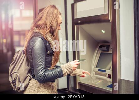 Giovane donna il ritiro di denaro dalla carta di credito presso ATM Foto Stock