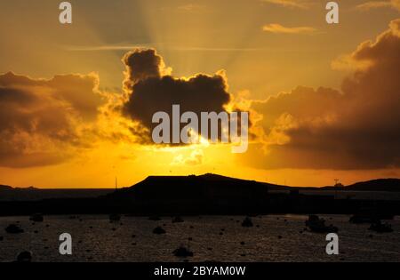 Il sole tramonta dietro una nuvola sul porto di St Marys sulle isole di Scilly.Cornovaglia UK Foto Stock