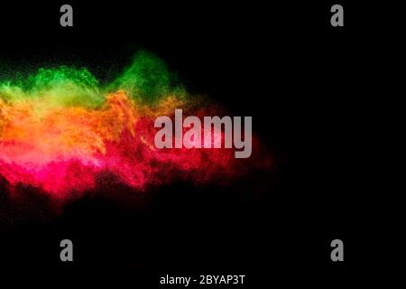 Esplosione di particelle di polvere colorate su sfondo nero. Primo piano di un'esplosione di colore isolata su nero Foto Stock