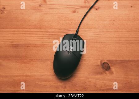 Mouse per computer su scrivania in legno, vista dall'alto della periferica nera con spazio per la copia Foto Stock