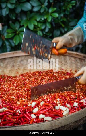 Peperoncini e aglio tagliati da donne lavoratrici in una ciotola di vimini sul mercato di strada nella città di Yangshuo, Cina Foto Stock