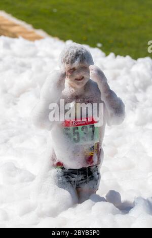 Poley Mountain, New Brunswick, Canada - 10 giugno 2017: Partecipazione alla raccolta fondi annuale 'mud Run for Heart'. Un bambino in un mucchio di saponette. Foto Stock