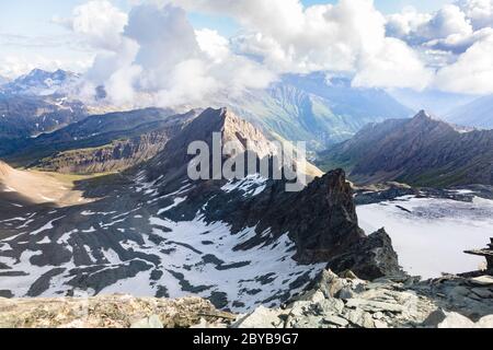 Catena montuosa e nubi di cumuli nelle Alpi austriache. Vista dalla strada per la cima rocciosa di Grossglockner, Kals am Grossglockner, Austria Foto Stock