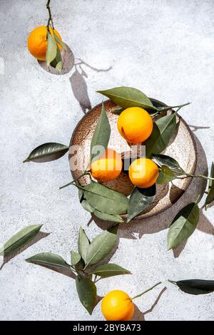 Arance intere con foglie di arance in piatto grigio. Su sfondo bianco vista dall'alto, piatto, estate e sano concetto. Foto Stock