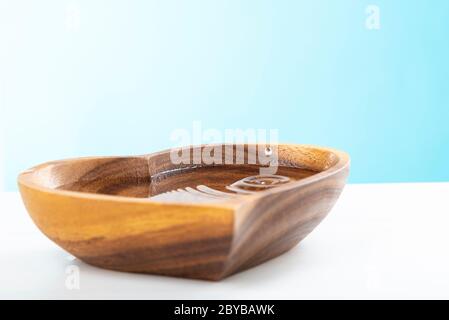Una goccia d'acqua cadde in una piastra di legno a forma di cuore. Concetto di giornata dell'acqua. Proteggere l'acqua potabile. Esaurimento dell'acqua potabile sulla Terra Foto Stock