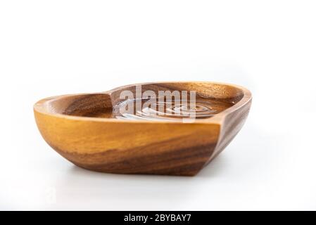 Una goccia d'acqua cadde in una piastra di legno a forma di cuore. Concetto di giornata dell'acqua. Proteggere l'acqua potabile. Esaurimento dell'acqua potabile sulla Terra Foto Stock