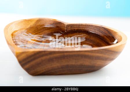 Una goccia d'acqua cadde in una piastra di legno a forma di cuore. Concetto di giornata dell'acqua. Proteggere l'acqua potabile. Esaurimento dell'acqua potabile sulla Terra Foto Stock