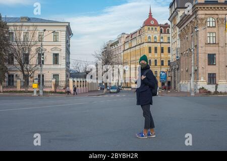 Kiev, Ucraina - 26 marzo 2020: Una ragazza in una maschera protettiva sul suo viso in Piazza Kontraktova su Podil nel centro di Kiev. Concetto di quarantena Foto Stock