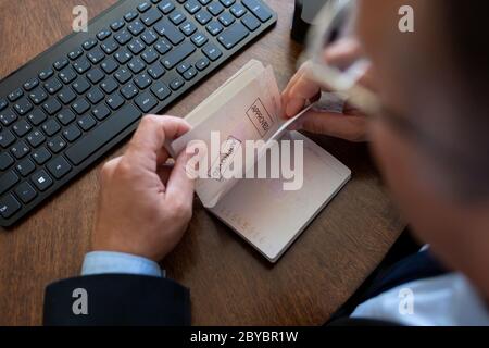 Ufficiale personalizzato che controlla un passaporto di viaggio. Screening dei passeggeri, viaggiatori per i sintomi del Coronavirus Cinese Covid-19 in aeroporto internazionale Foto Stock