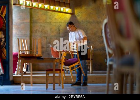 Il cameriere prepara il Ristorante per la riapertura dopo la quarantena Foto Stock