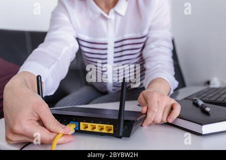 mano e cavo di rete lan con persone che lavorano su router wireless, Foto Stock