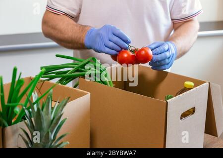 Fondi di soccorso e donazioni per il coronavirus. Volontari nella maschera medica protettiva e guanti per le mani Putting Food in Donation Box. Donazioni di beneficenza. Foto Stock