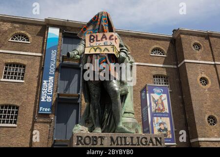 Ore prima che fosse rimossa dalla fondazione Canal and River Trust, la statua del mercante di schiavi, Robert Milligan si trova coperto da attivisti della materia Black Lives fuori dal Museo dei Docklands di Londra sul West India Quay, un tempo il magazzino più lungo del mondo pagato dai profitti della schiavitù, il 9 giugno 2020, A Londra, Inghilterra. Dopo le proteste di George Floyd negli Stati Uniti e nel Regno Unito Black Lives, i gruppi che chiedono la rimozione di statue e nomi di strada con collegamenti al commercio degli schiavi, Milligan e altre statue di profitatori della schiavitù britannica, sono diventati un punto di protesta. Foto Stock